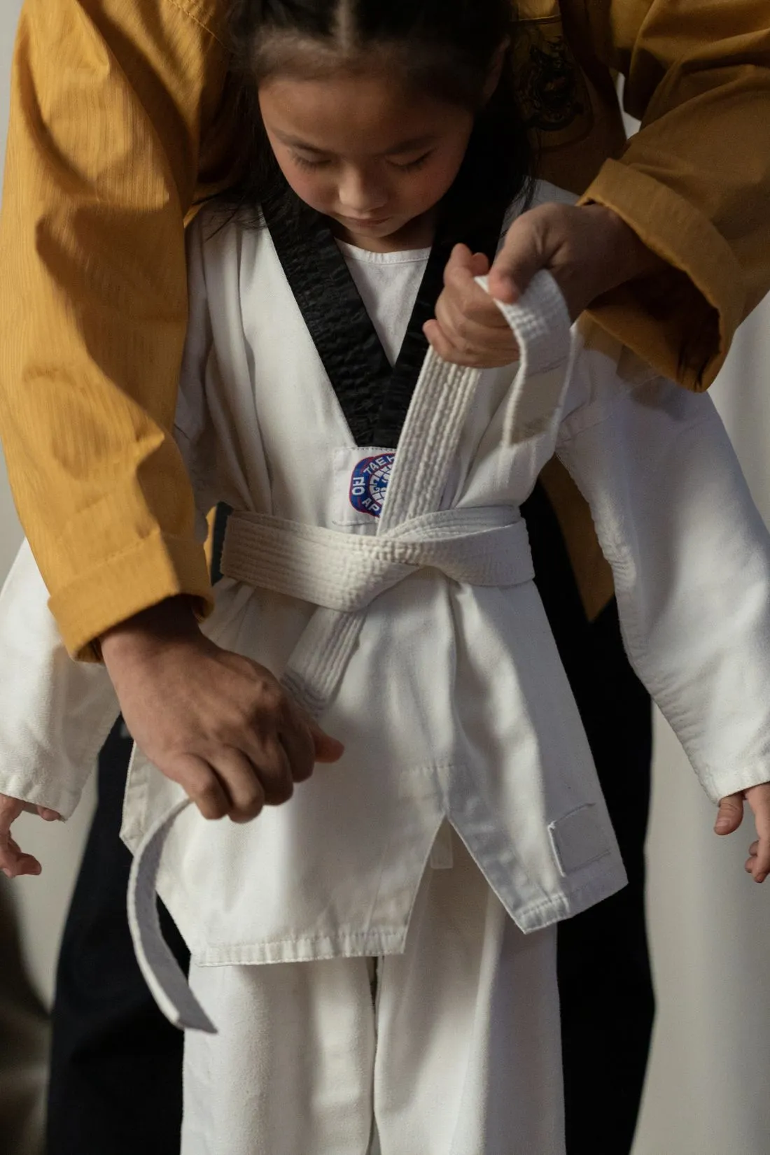 An instructor tying a belt on a young student